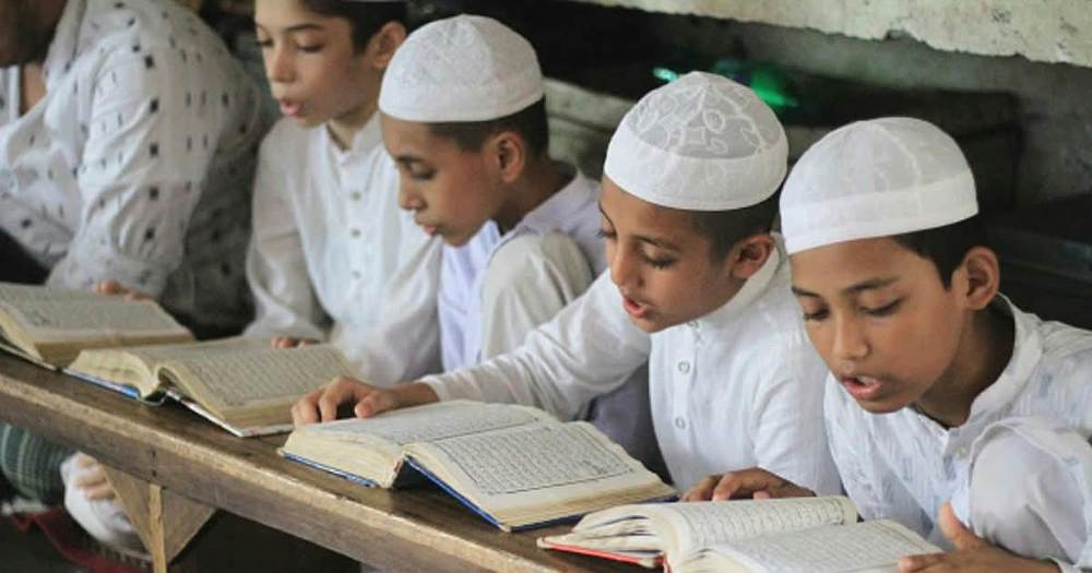 طلبہ ایک قطار میں بیٹھ کر قرآن مجید پڑھتے ہوئے