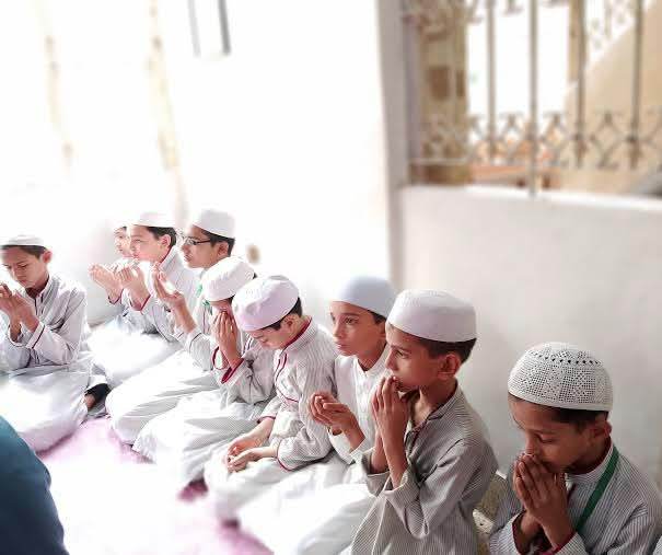 طلبہ ایک قطار میں بیٹھ کر اجتماعی دعا کرتے ہوئے